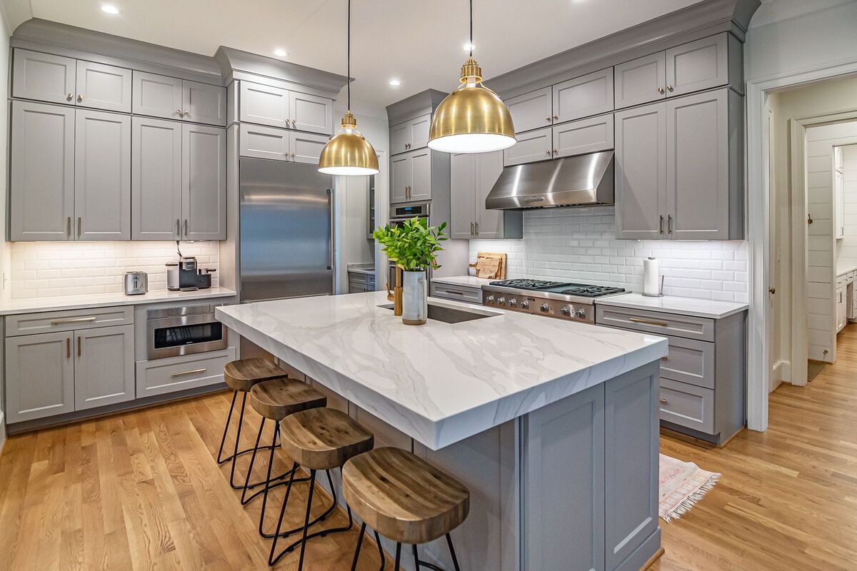 Two brass pendant lights hung over a marble kitchen island