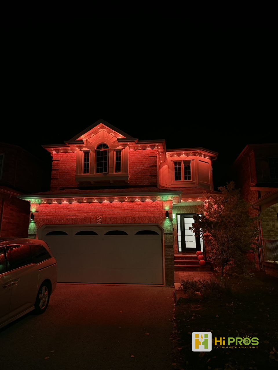 Two-storey brick house at night with permanent lights under every roof edge, glowing red